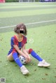 A woman sitting on the ground with a soccer ball.