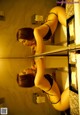 A woman in a black lingerie is looking at herself in the mirror.