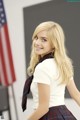 A woman in a school uniform posing in front of an American flag.