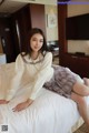 A woman sitting on top of a bed in a hotel room.