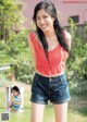 A young woman in a red top and denim shorts posing for a picture.