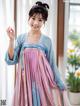 A woman in a pink and blue hanbok posing for a picture.