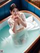 A woman in a white dress sitting in a bathtub.