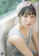 A woman with a pink headband sitting on a window sill.