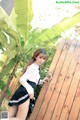 A woman in a school uniform leaning against a wooden fence.