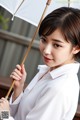 A woman in a white shirt holding an umbrella.