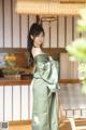 A woman in a green kimono standing on a porch.