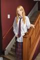 A woman in a school uniform standing on a set of stairs.