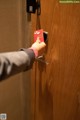 A person opening a door with a red card in their hand.