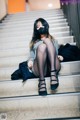 A woman wearing a face mask sitting on a set of stairs.