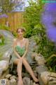 A woman in a green dress sitting on a stone wall.