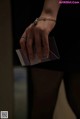 A woman in a black dress holding a business card.