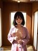 A woman in a pink kimono standing in a room.