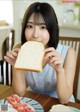 A woman sitting at a table eating a piece of bread.