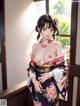 A woman in a kimono standing in front of a window.