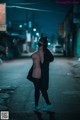 A woman wearing a cat mask standing in the middle of a street.