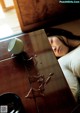 A woman laying on a bed next to a table with a cup of coffee.