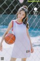 A woman in a basketball uniform holding a basketball.