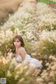 A woman in a white dress sitting in tall grass.