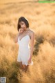 A woman in a white dress standing in a field.