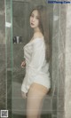 A woman in a white shirt standing in a shower.